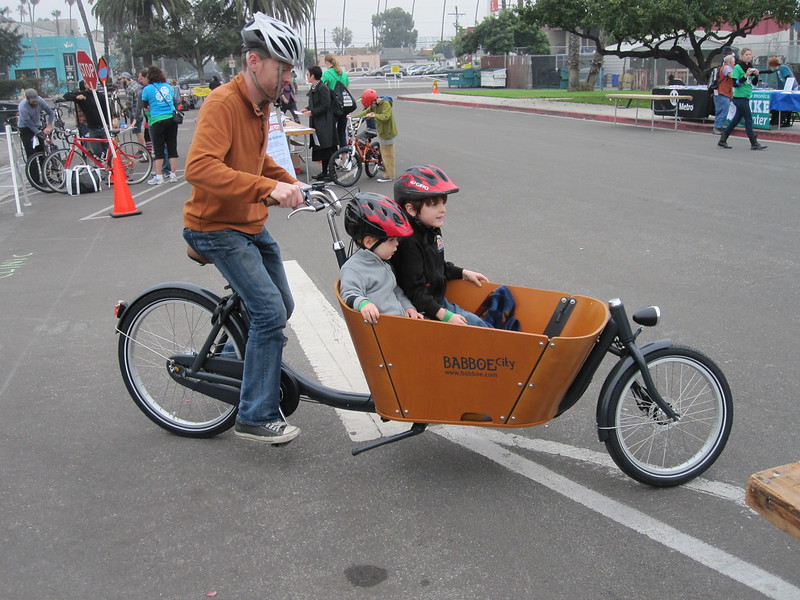 Father rides a Babboe Cargo Bike with two children
